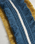 Cuscino quadrato bianco con frange blu e ocra. L'oca nera