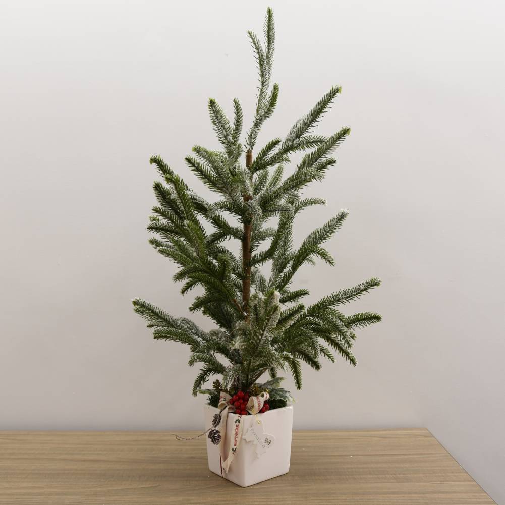 Albero di pino innevato piccolo in vaso di ceramica quadrato e decori natalizi. Fiori di Lena